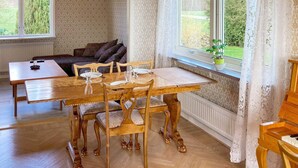 Uma sala de jantar acolhedora com uma mesa e cadeiras de madeira, um sofá e um piano.