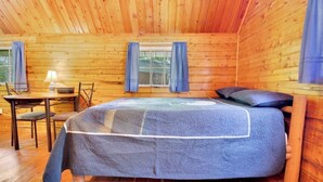 A cozy wooden cabin room with a bed, a table with chairs, and a window with curtains. - Rustic Cabin in Bloomington with Views (Bloomington)