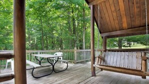 A wooden deck with a picnic table and a swing. - Rustic Cabin in Bloomington with Views (Bloomington)
