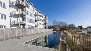 A modern building with multiple balconies and a narrow waterway beside it. - Apartment on the 2nd Floor for Family (Middelkerke)