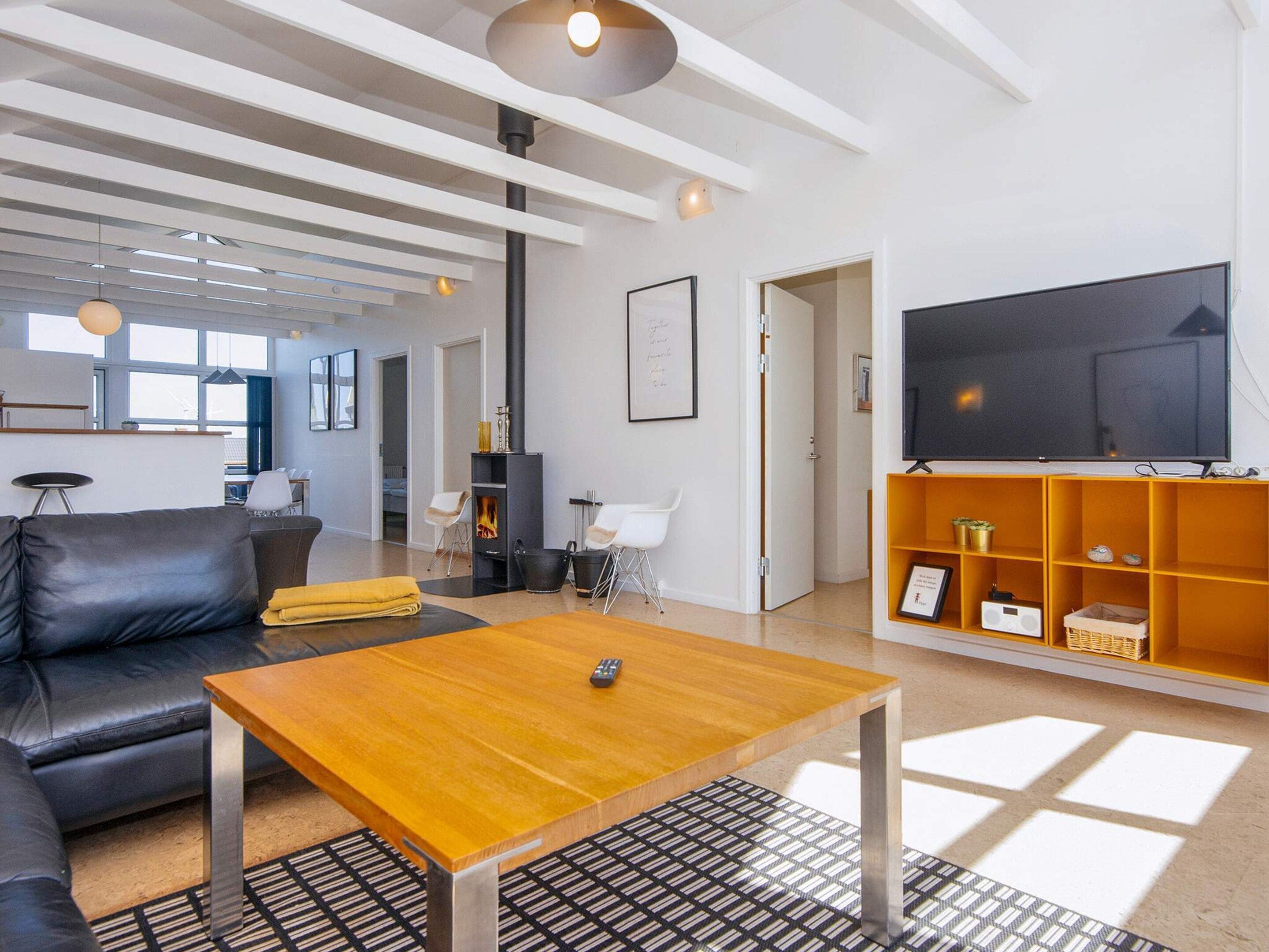 Una sala de estar moderna con un sofá, una mesa de centro, chimenea, televisor y una estantería.