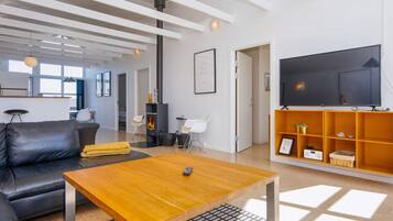 Una sala de estar moderna con un sofá, una mesa de centro, chimenea, televisor y una estantería.