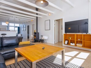 A modern living room with a sofa, coffee table, fireplace, TV, and a bookshelf. - 6 Person Holiday Park Home in Glesborg (Glesborg)