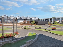 Un parque infantil con una estructura para escalar, una piscina pequeña y una zona de estar con una mesa y sillas.