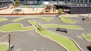 Un parque infantil con un arenero, columpios y un tobogán.