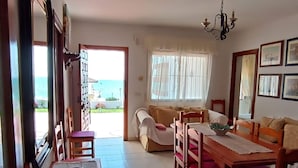 Un coin repas avec une table et des chaises, un canapé et une vue sur la mer par une fen être.