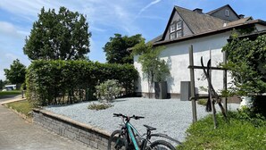 A residential area with a house, a gravel driveway, and a parked bicycle.
