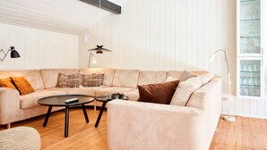 A modern living room with a sectional sofa, two coffee tables, and a floor lamp. - 8 Person Holiday Home in Nexo-by Traum (Nexø)