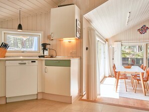 A modern kitchen with a Siemens dishwasher, a coffee machine, and a window with a view of trees.