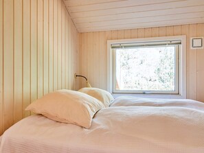 Une chambre avec un lit simple, une fenêtre et des murs en bois.
