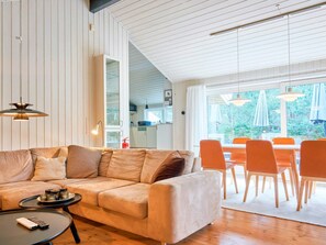 A modern living room with a sofa, a coffee table, and a dining area with chairs and a table.