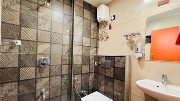Un baño con baldosas estampadas, inodoro, lavamanos y ducha.