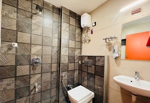 A bathroom with patterned tiles, a toilet, a sink, and a shower. - Home Escape 1BHK Retreat Nr Saket Square (Indore)
