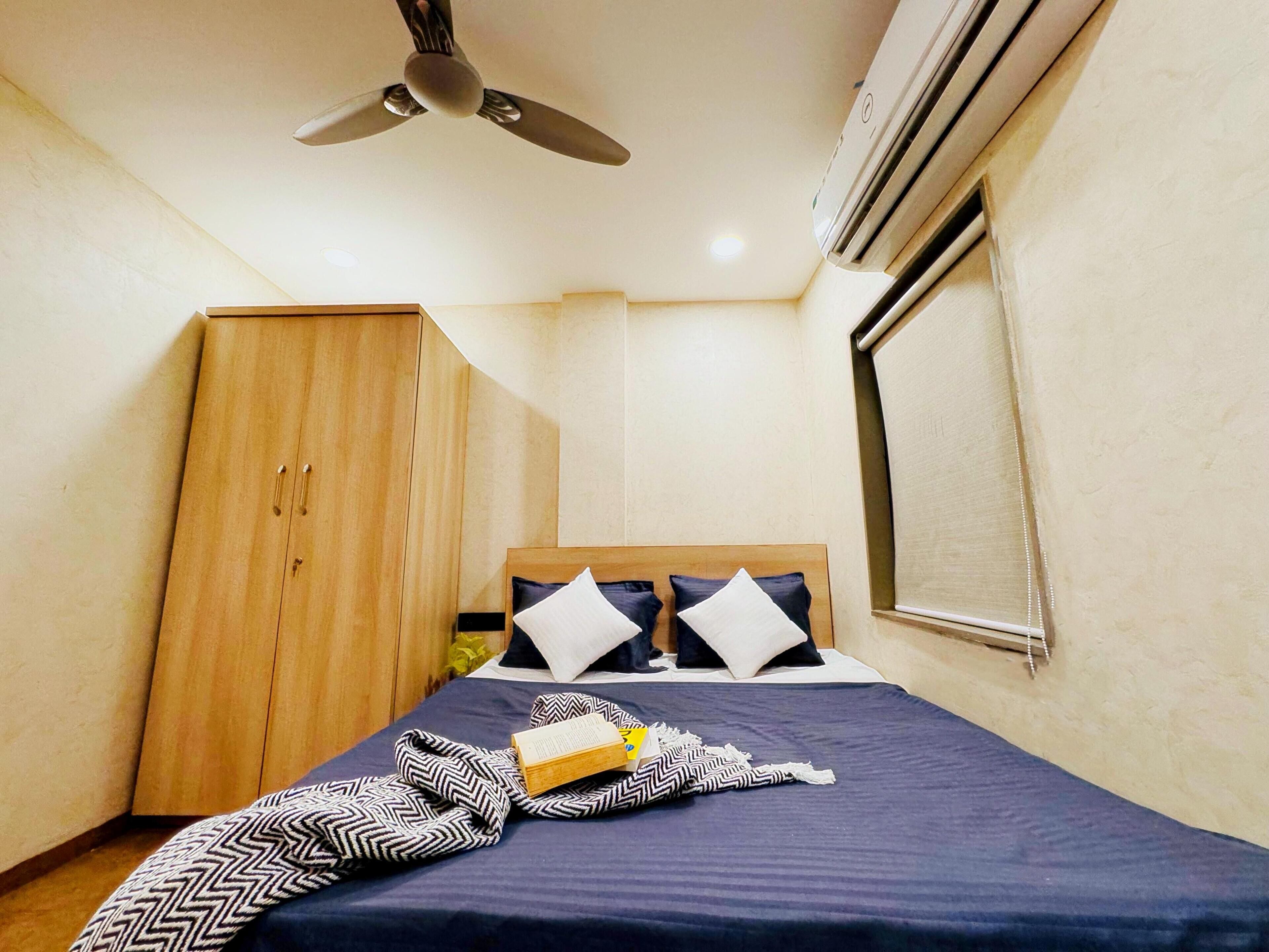 Ein Schlafzimmer mit einem Bett, einem Holzschrank, einem Deckenventilator und einer Klimaanlage.