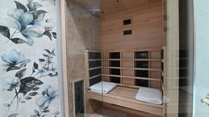 Un sauna avec un banc en bois, des murs en verre et une fresque florale sur l’un des murs.