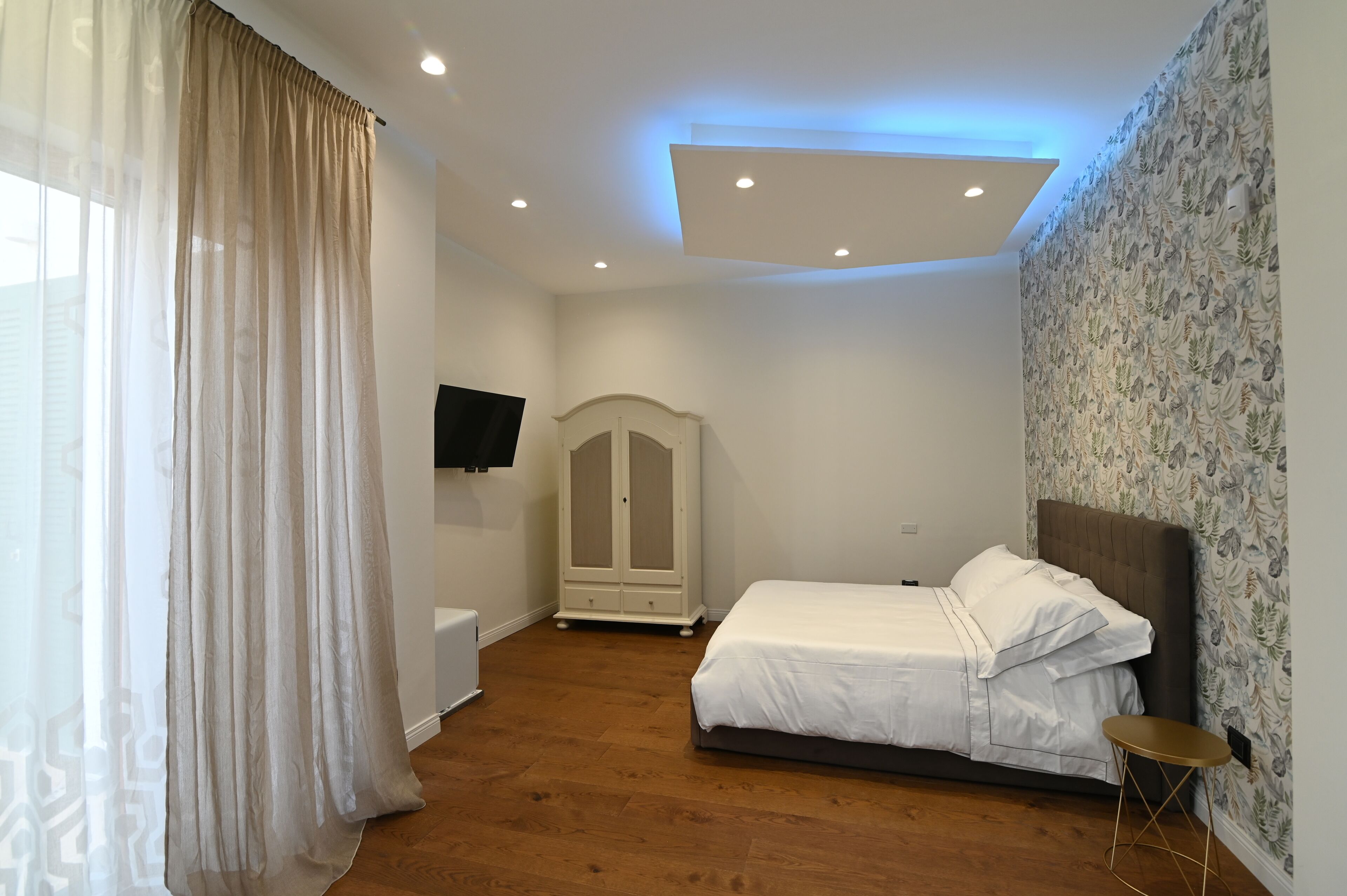 Une chambre à coucher avec un lit, une armoire, une télévision et une petite table.