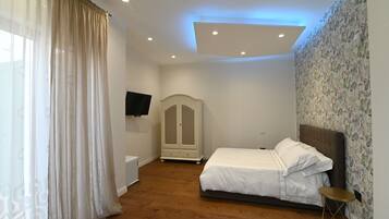 Une chambre à coucher avec un lit, une armoire, une télévision et une petite table.