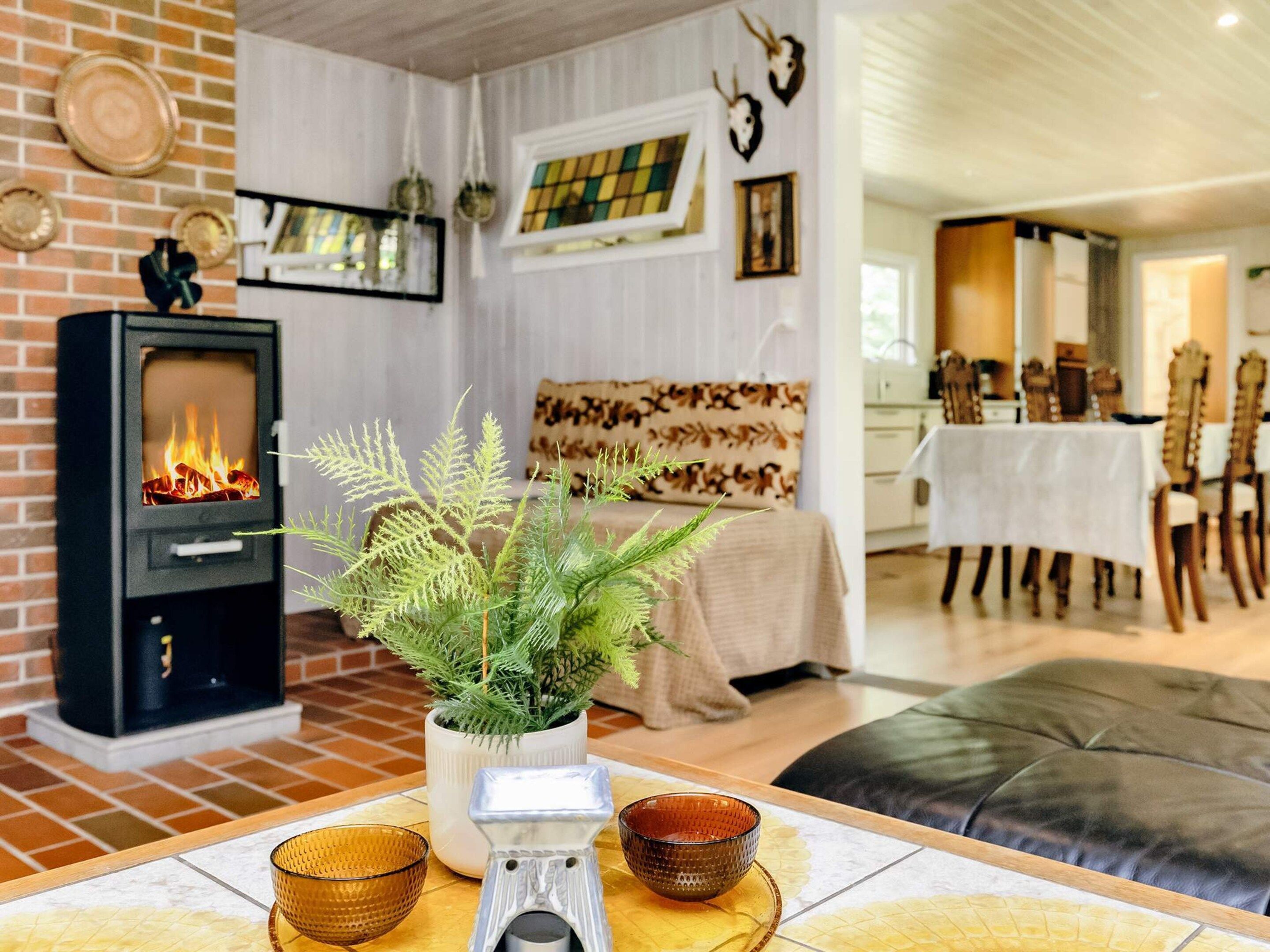 A cozy living room with a fireplace, a dining area with a table set for two, and a kitchen in the background.