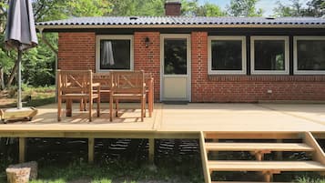 A brick building with a wooden deck, a covered seating area, and a staircase leading to an upper level.