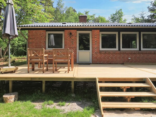 A brick building with a wooden deck, a covered seating area, and a staircase leading to an upper level.