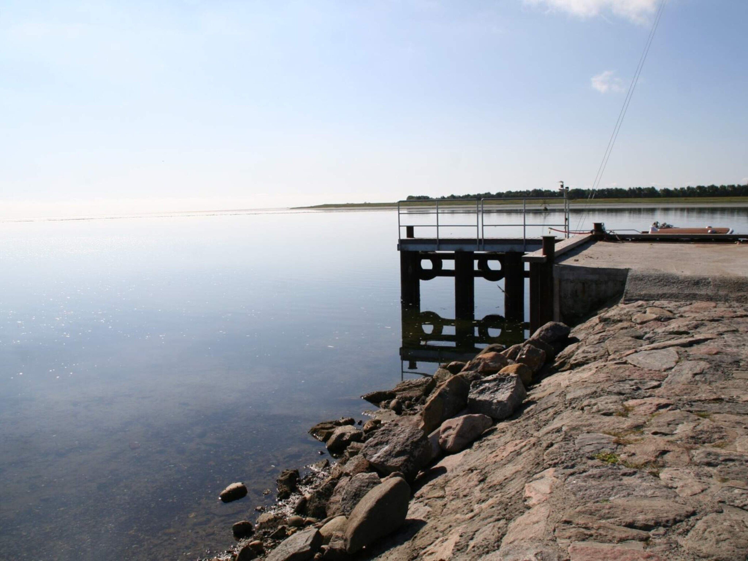 Un lac paisible, bordé d’une rive rocheuse et doté d’une jetée en bois qui s’avance dans l’eau.