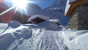 A snow-covered mountain path leading to a wooden cabin with a stone wall. - Holiday Home Lazins Comfortable Vacation Home (Moso in Passiria)
