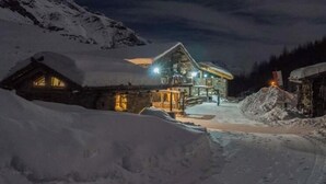 A snow-covered mountain lodge at night with illuminated windows and a well-lit entrance. - Holiday Home Lazins Comfortable Vacation Home (Moso in Passiria)