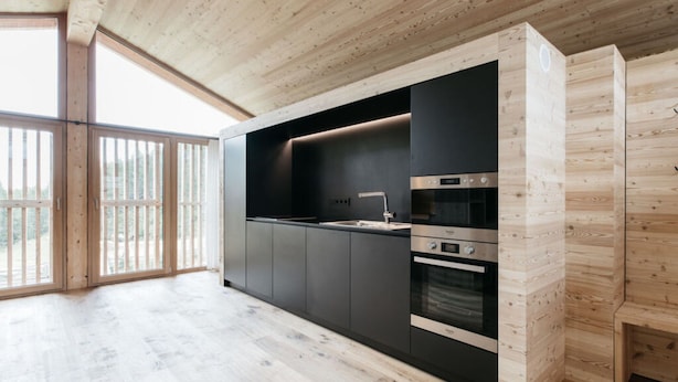 A modern kitchen with wooden cabinetry, built-in appliances, and large windows. - Holiday Home Lazins Comfortable Vacation Home (Moso in Passiria)