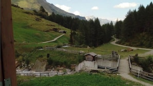 A scenic view from a wooden balcony overlooking a mountainous landscape with a bridge and a small building. - Holiday Home Lazins Comfortable Vacation Home (Moso in Passiria)