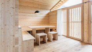 A wooden interior with a high ceiling, a table with two stools, and large windows. - Holiday Home Lazins Comfortable Vacation Home (Moso in Passiria)