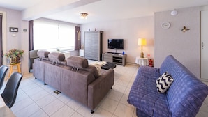 A modern living room with a sofa, a television, a lamp, and a cabinet. - Apartment on the Third Floor (Middelkerke)