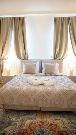 Ein ordentlich bezogenes Bett mit einer gemusterten Tagesdecke, zwei Kissen und einem Paar gefalteter Handtücher.