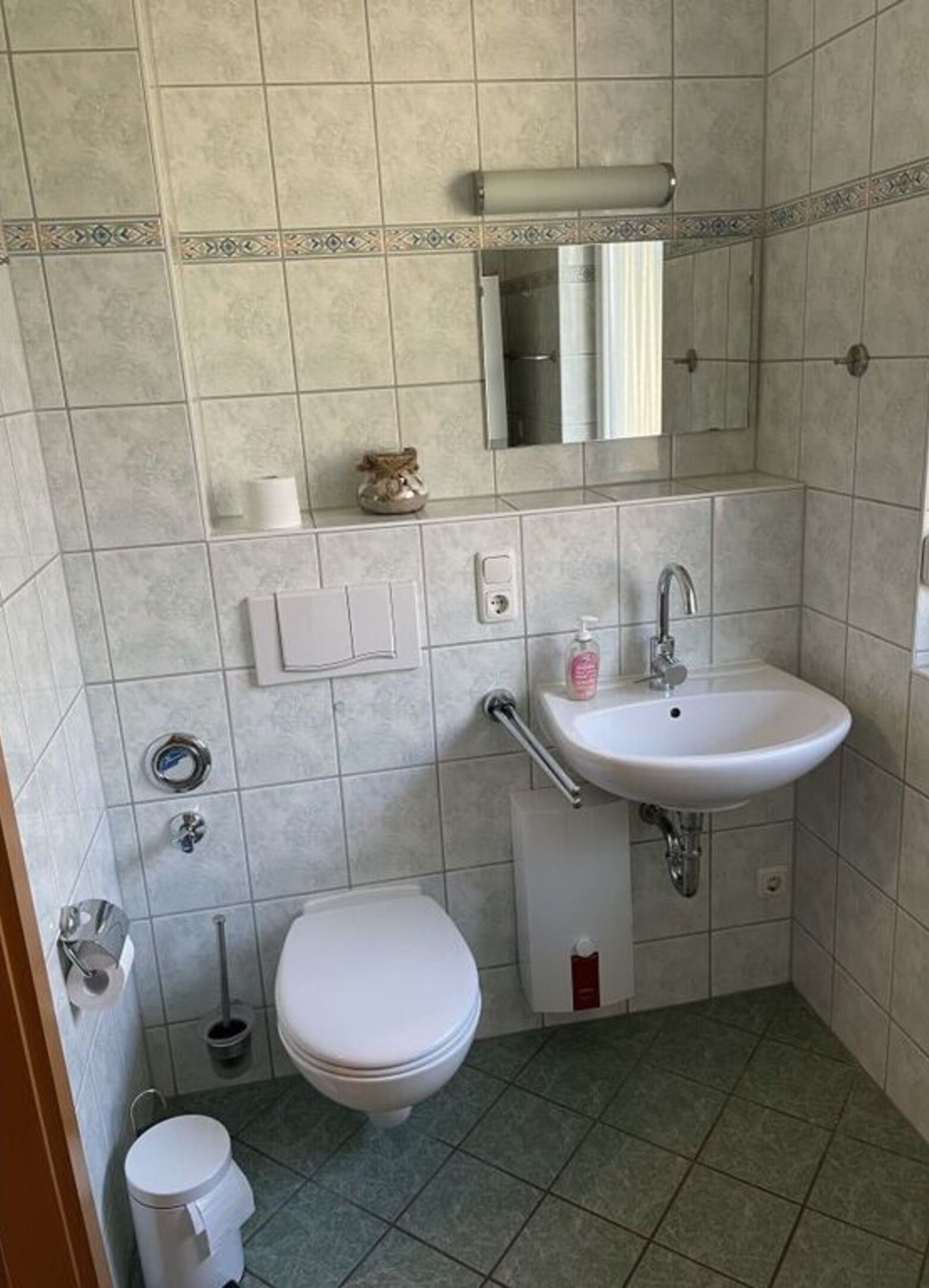 Een kleine badkamer met toilet, wastafel en spiegel.