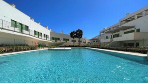 A swimming pool with clear blue water, surrounded by modern buildings with balconies and windows. - Belvilla by OYO Apartamento Moja!car (Mojacar)
