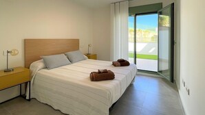 A modern bedroom with a large bed, two bedside tables, a nightstand, and a sliding glass door leading to a balcony. - Belvilla by OYO Apartamento Moja!car (Mojacar)