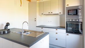 A modern kitchen with a built-in oven, microwave, and a sink with a kettle. - Holiday Home in Koksijde With Garden (Koksijde)