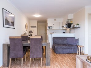 Een modern appartement met een eethoek, een bank en een kitchenette.