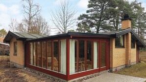 A small brick house with a glass extension, a chimney, and a paved entrance. - 6 Person Holiday Home in Vaeggerlose (Vaeggerlose)