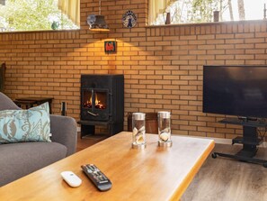 Una sala de estar con chimenea de ladrillo, televisor y sofá.