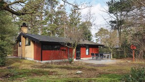 A small, single-story building with a red exterior and a black roof, surrounded by trees and a grassy area. - 6 Person Holiday Home in Vaeggerlose (Vaeggerlose)