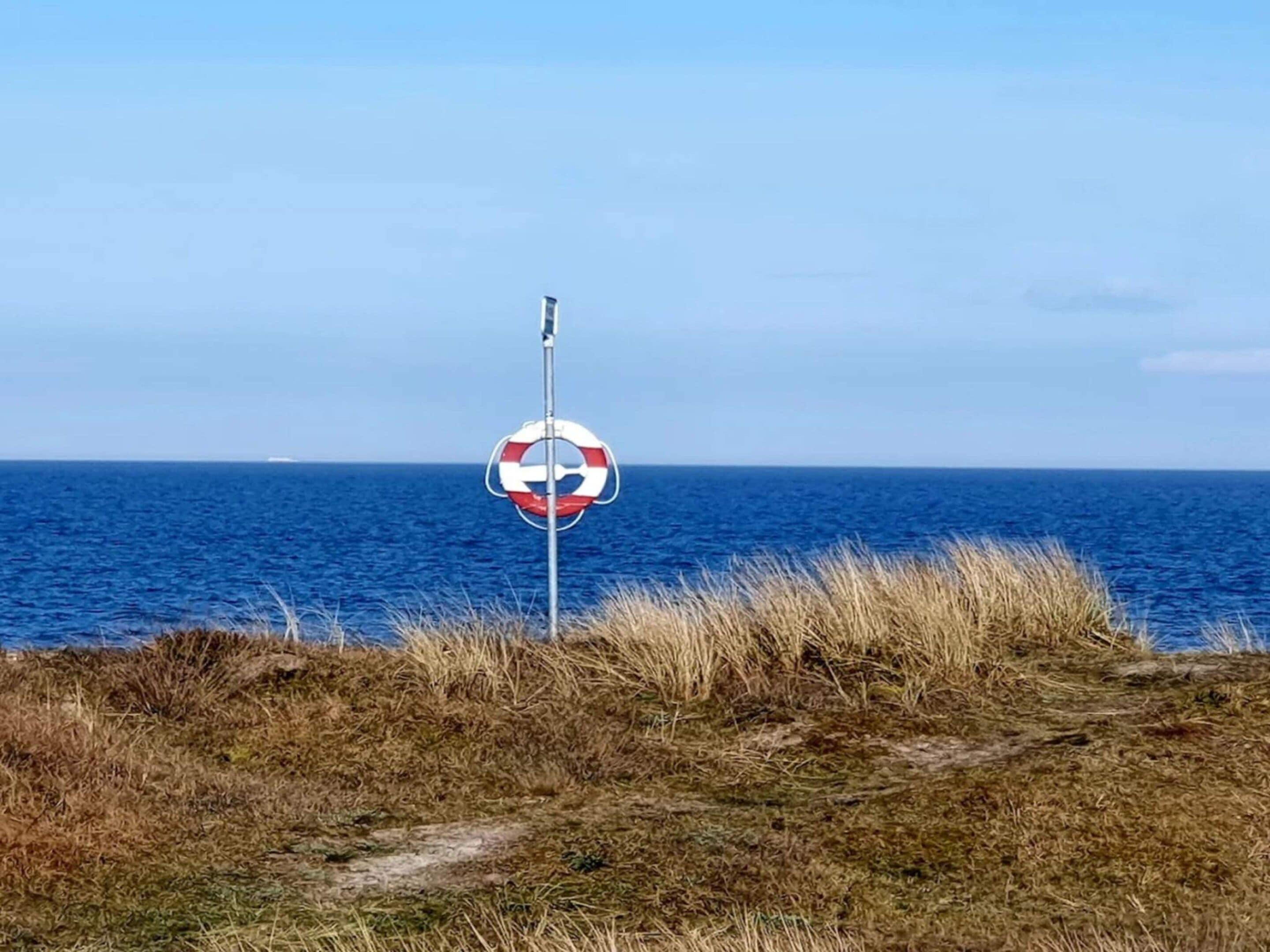 Un letrero de boya en un poste cerca del mar.