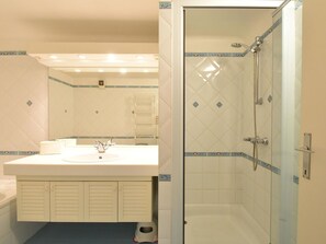 A bathroom with a white sink, mirror, and shower. - Gianina Apartment for Five Person in De Haan (De Haan)