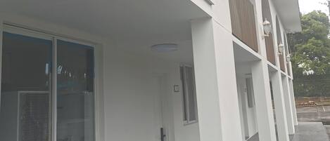 Un edificio con fachada blanca, amplias ventanas y un paseo techado con columnas.
