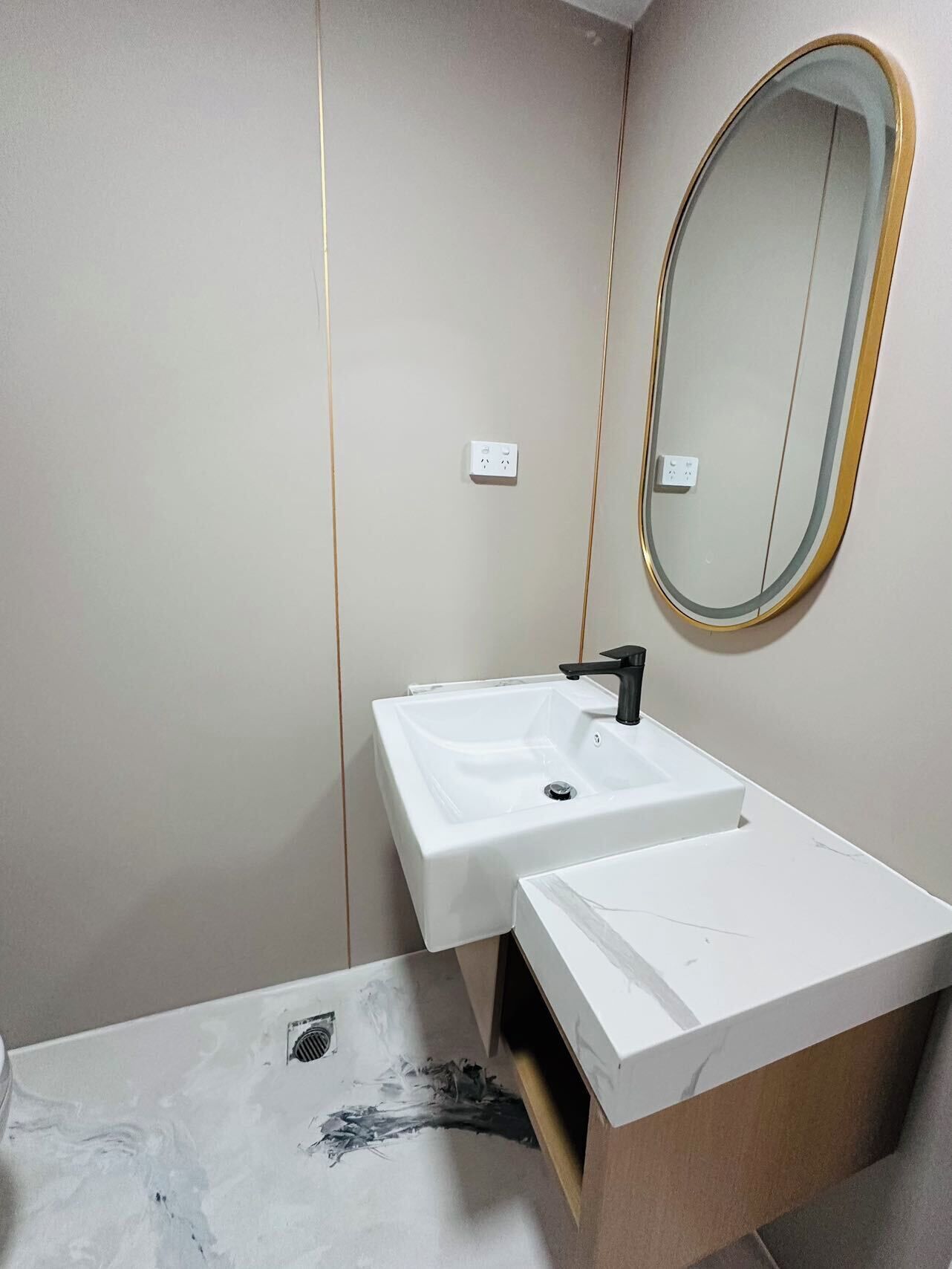 A bathroom with a white sink, a black faucet, a mirror with a gold frame, and a marble countertop.