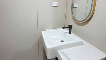Un baño con un lavamanos blanco, un grifo negro, un espejo con marco dorado y una encimera de mármol.