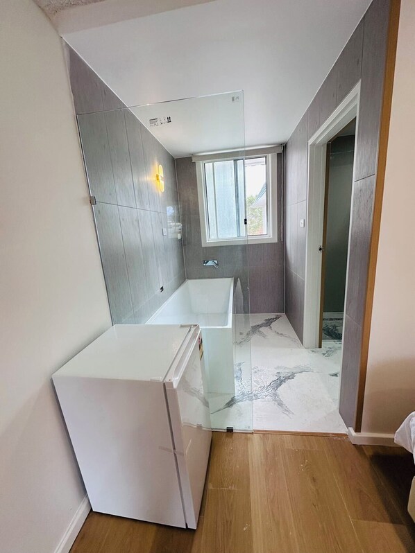 A modern bathroom with a bathtub, a toilet, and a shower area.