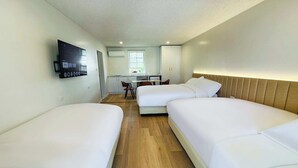 A hotel room with two single beds, a small desk with a chair, a TV mounted on the wall, and a window providing natural light. - Venus Resort (Long Jetty)