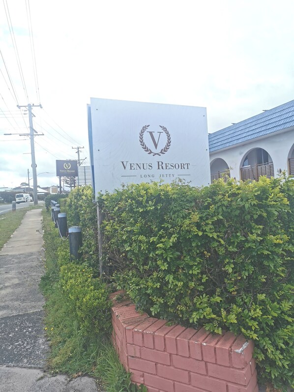 A sign for Venus Resort with a logo, name, and location.