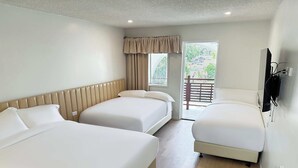 A hotel room with three beds, a wooden floor, a window with a view of greenery, and a TV mounted on the wall. - Venus Resort (Long Jetty)