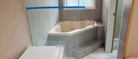 A compact bathroom with a bathtub, a shower area, and a toilet.